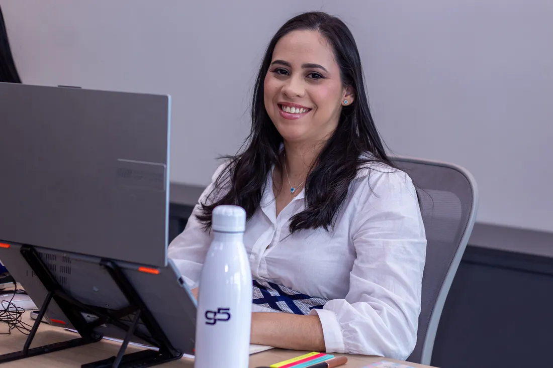 Consultora da G5 sorrindo na mesa de trabalho